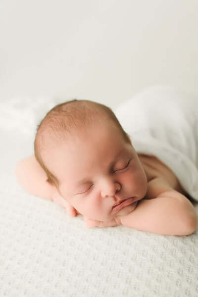 newborn baby sleeping on white fabric
