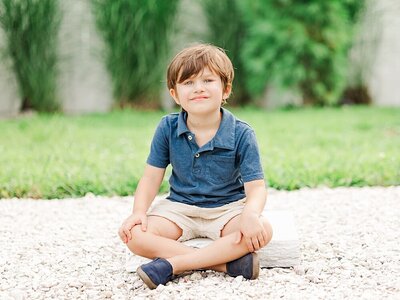 Boy sitting on white wood on white stone outdoors.