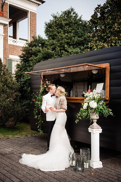 1920s bride and groom kissing at mobile bar trailer