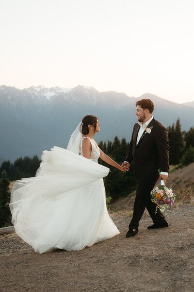 Couples walks with the beautiful Olympic mountains behind them during their Olympic National Park Elopement