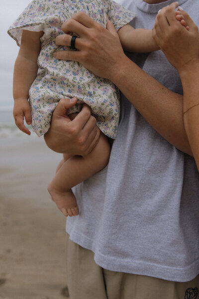 parents hands holding little  girl