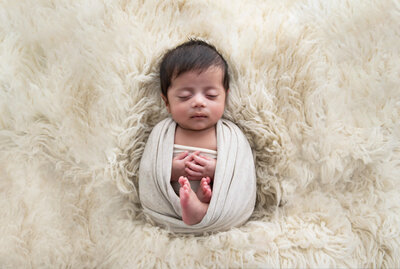 Newborn boy wrapped in beige for his newborn photography session in Burlington, Ontario.