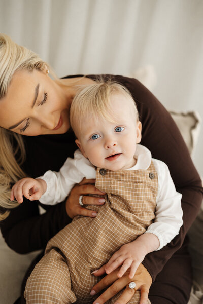 A mother holds her little baby styled in brown and white, taken in the studio by canterbury photographer lucy jane
