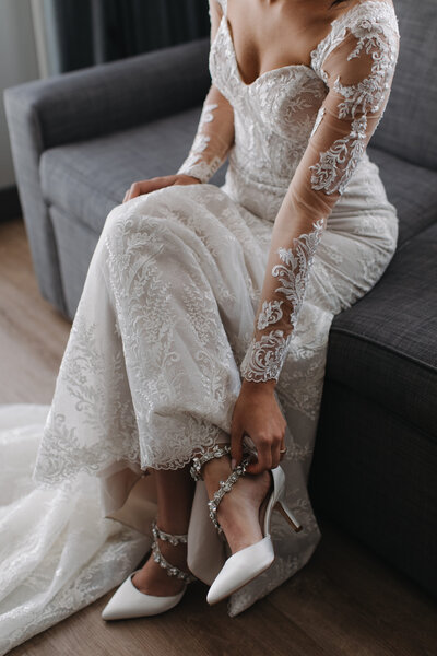 bride sitting on a couch adjusting her high heel while wearing her wedding gown