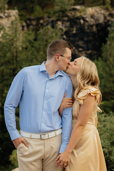 A man kissing his girlfriend's forehead.