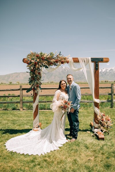 bride and groom sitting out side of LDS temple holding light pink orange and blue bouquet