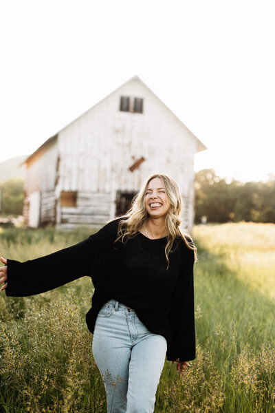 elopement photographer smiling and walking through a field in Colorado.