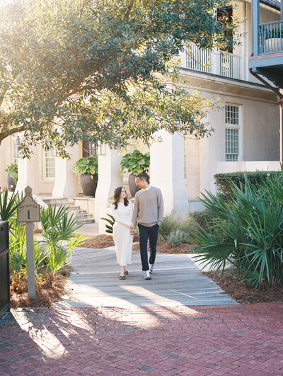 Couple walking together holding hands on a sidewalk with glowy sunlight in the background