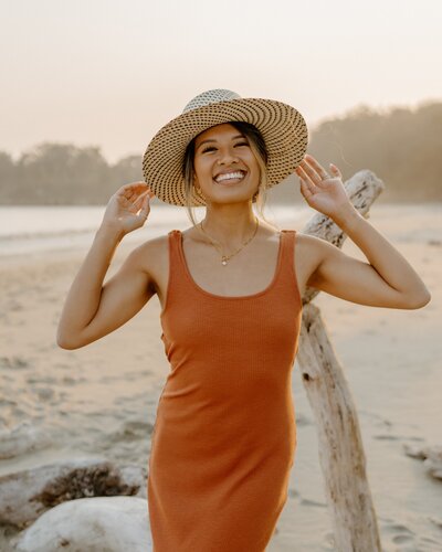 woman smiling while holding hat