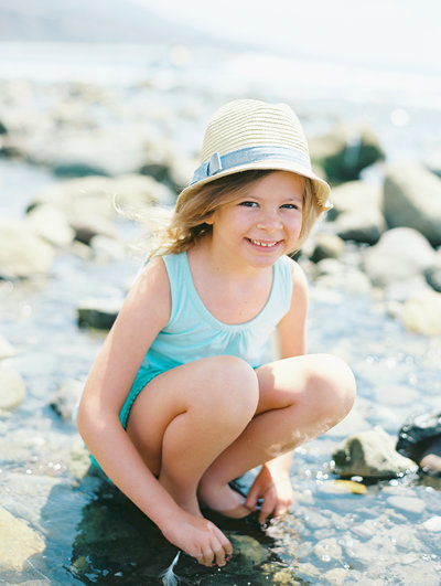 A young girl smiles at the camera during her Malibu portrait session at Leo Carrrillo beach