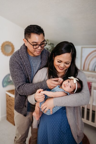 newborn photo with mom and dad looking happily down at baby daughter