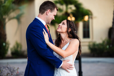 Bride and groom embracing and holding hands under a neon sign with candles at their wedding reception at Grand Tradition Estate and Gardens venue in San Diego.
