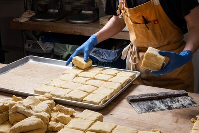 Baker cutting and preparing gluten-free pastry dough on a floured surface at Grain Artisan Bakery.