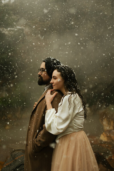 A couple snuggled up in the middle of a snow storm