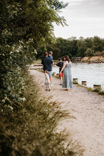 Family photo taken overlooking the water in Annapolis, Maryland with family walking away from camera wearing different shades of blue and gray.