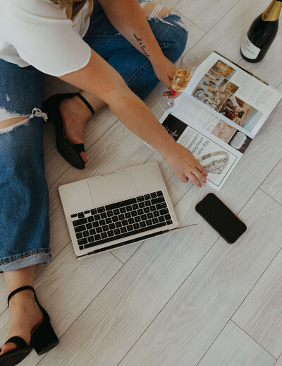 A hand on a laptop and champagne glass, representing the full service event planning and wedding coordinator services of Bubbly Bride Planning. 