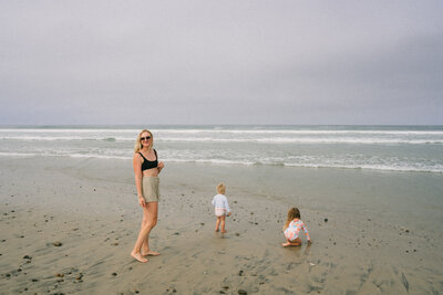 woman smiling on a beach with two kids