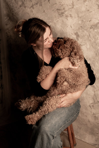 headshoot of business owner cuddling dog in studio photoshoot