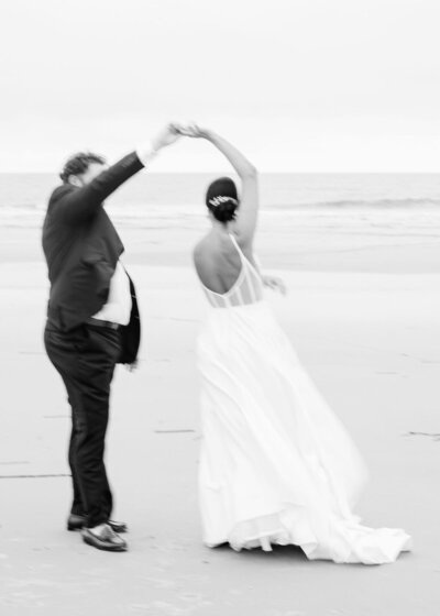 groom twirls bride on beach