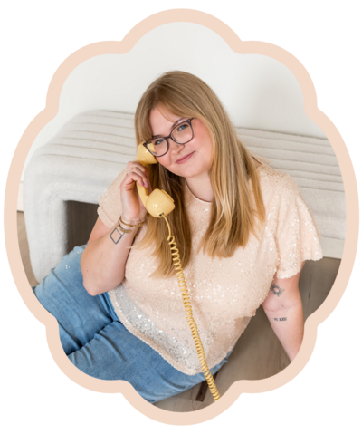 headshot photograph of blonde brand design business owner wearing glasses smiling at the camera holding yellow retro phone
