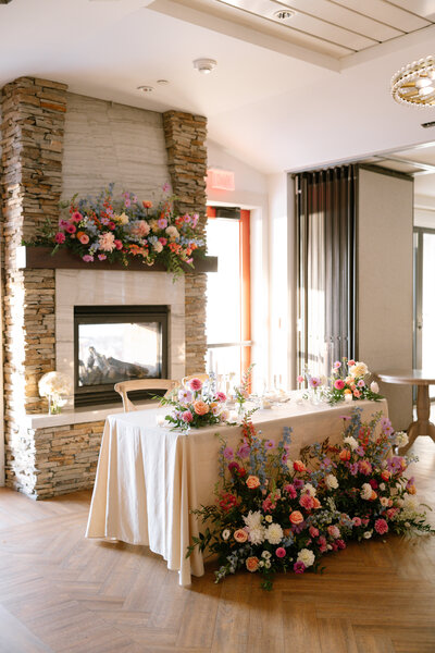 Stylish wedding reception tablescape with lush floral centerpiece of blush roses and textured greenery by Leigh Florist.