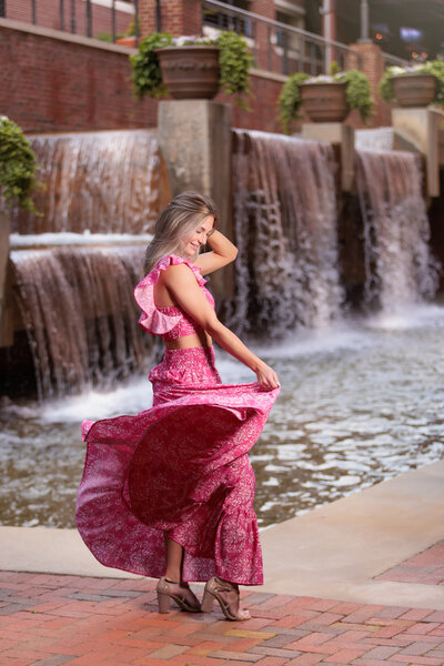 High School Senior wearing a pink outfit with long skirt with waterfalls behind her