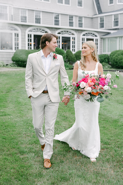 a bride and groom walking on the lawn of their wedding venue