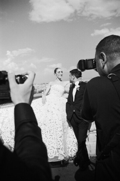 out of focus photo of a bride laughing as her groom lifts her over his shoulder