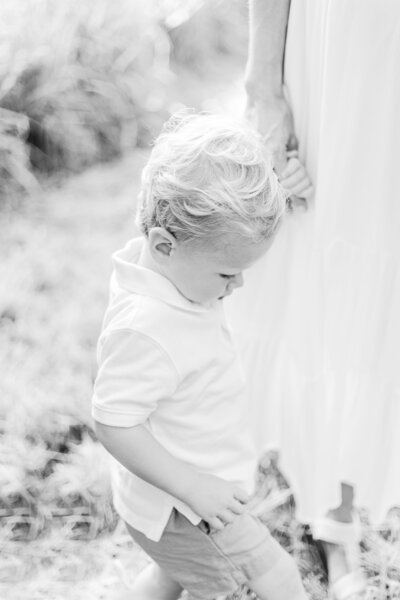 A black and white image of a mother holding her son's hand during photo session with Cape Cod photographer Corinne Isabelle
