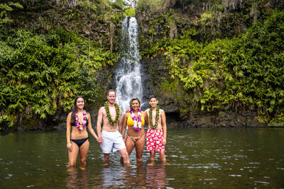 Family standing in waterfall in Hawaii by a team of Big Island Photographers
