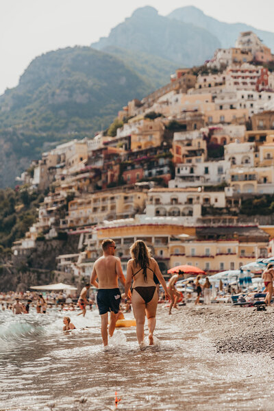 couple walk together on beach in positano