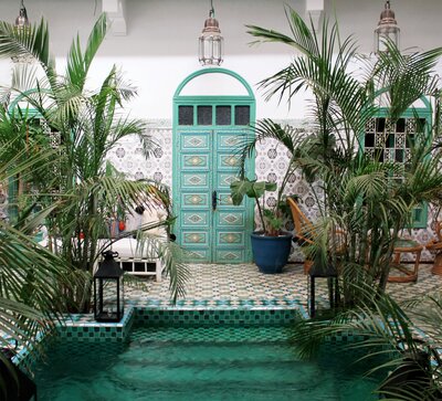Bright teal door leading to a black and white tiled pool