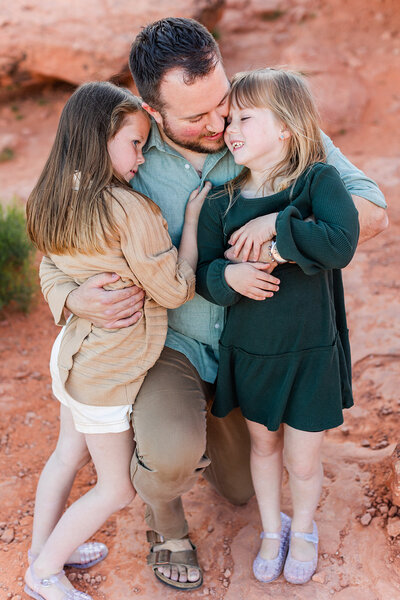dad hugging his two daughters