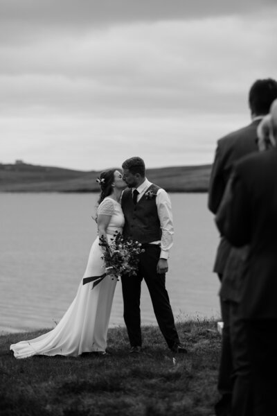 bride and groom embracing near water