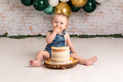 baby in denim overalls eating cake by Philadelphia Newborn Photographer