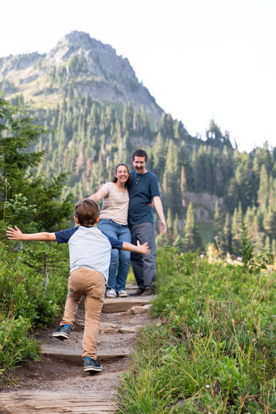 Young boy running into the arms of his mom and dad at Tipsoo Lake for summer family photography session