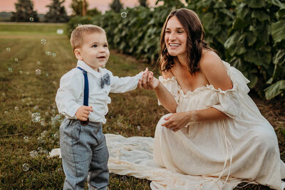 mom and son playing with bubbles outside maternity session near eau claire wi