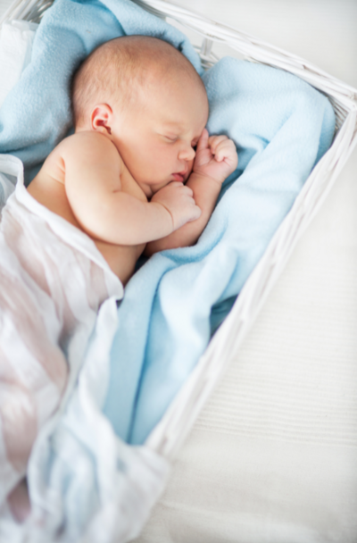 The tranquility of a sleeping baby boy in a cozy blue cradle, wrapped in a soft white blanket, creating a serene scene of comfort and warmth.