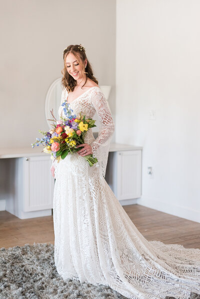 Bride smiles down at her bouquet inside the venue The Barn at Raccoon Creek in Littleton, Colorado