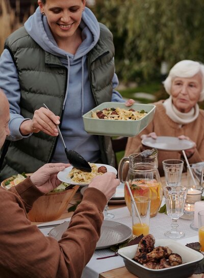 Smiling woman outdoors holding a bowl of food representing mindful eating and gentle nutrition therapy from The Reclaimed Table program at Rooted & Nourished Psychotherapy
