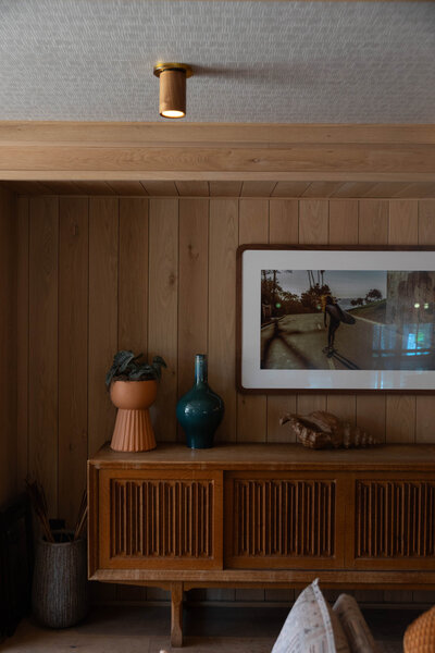 A credenza with pottery and wooden paneling behind it.