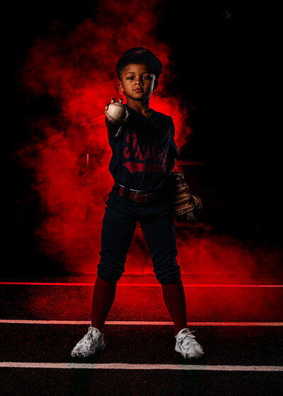 a youth baseball player holds the ball out during a team photo shoot