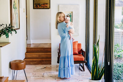 serene photo of mother cuddling her new baby in a room full of windows and light