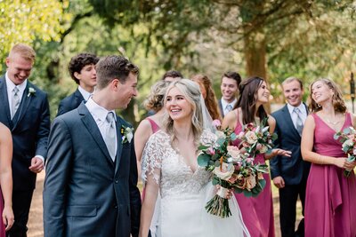 Bride and Groom walking and smiling while bridesmaid and groomsmen are behind them
