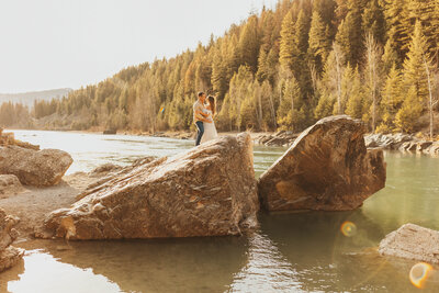 couple posing on large rock in lake