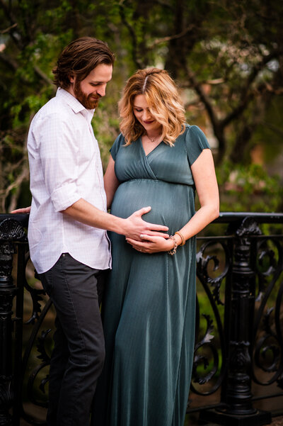 Expecting mother in a flowing dress, cradling her baby bump at sunset during a maternity session at Lafayette Park in St. Louis.
