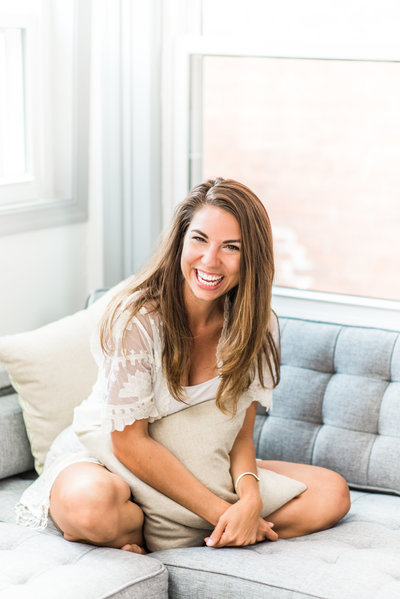 Stephanie Messick on her sofa laughing at the camera.