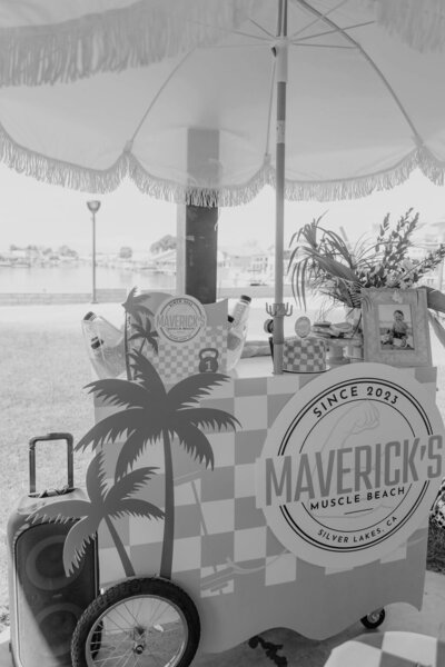 Black and white image of muscle beach party themed bar cart with umbrella at a birthday party planned by Fancy Chancey in San Diego CA
