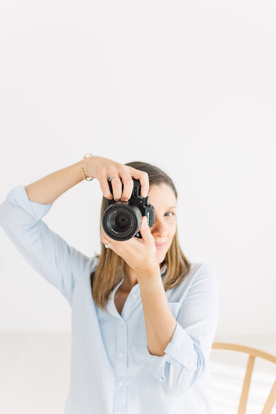 a photographer sits on a chair and looks in the viewfinder of her Sony camera.