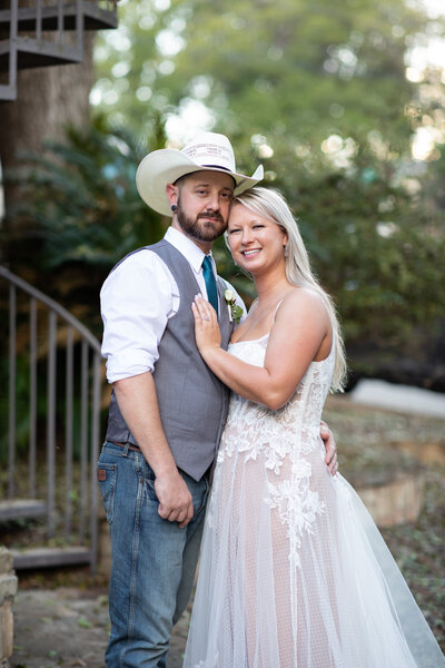 An Austin-based wedding photographer captures a bride and groom posing for a photo in a cowboy hat.